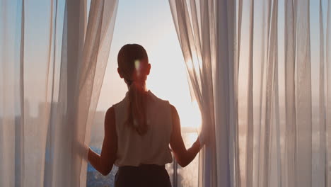 Mujer-De-Negocios-Abriendo-Cortinas-En-La-Habitación-Del-Hotel-Mirando-Por-La-Ventana-Al-Nuevo-Día,-Una-Exitosa-Mujer-Independiente-Planificando-Con-Anticipación-Al-Amanecer.