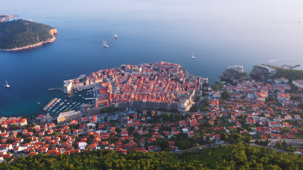 Splendida inquadratura rivelatrice volando in avanti verso il mare e la città vecchia di Dubrovnik, Croazia, al tramonto, con montagne, funivia e mare in 4k