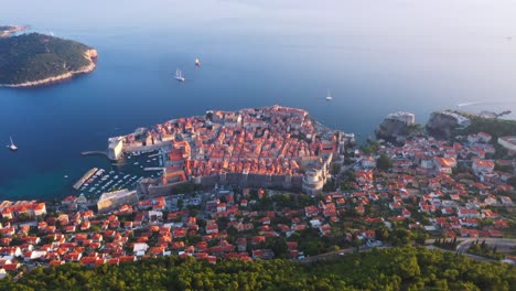 stunning reveal view flying forward into sea and old town of dubrovnik, croatia durning sunset with mountains, cable car and sea in 4k