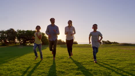 Una-Joven-Familia-Blanca-Corriendo-Hacia-Una-Cámara-En-Movimiento-En-Un-Parque