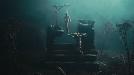 a miniature scene of the mummified dolls hanging on the gallows at night
