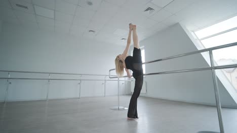 chica en forma con ropa negra actuando contemporáneamente. bailarina muestra movimientos fluidos, cuerpo y manos ondas en la habitación blanca. coreografía de danza de ballet moderno. joven se mueve suavemente