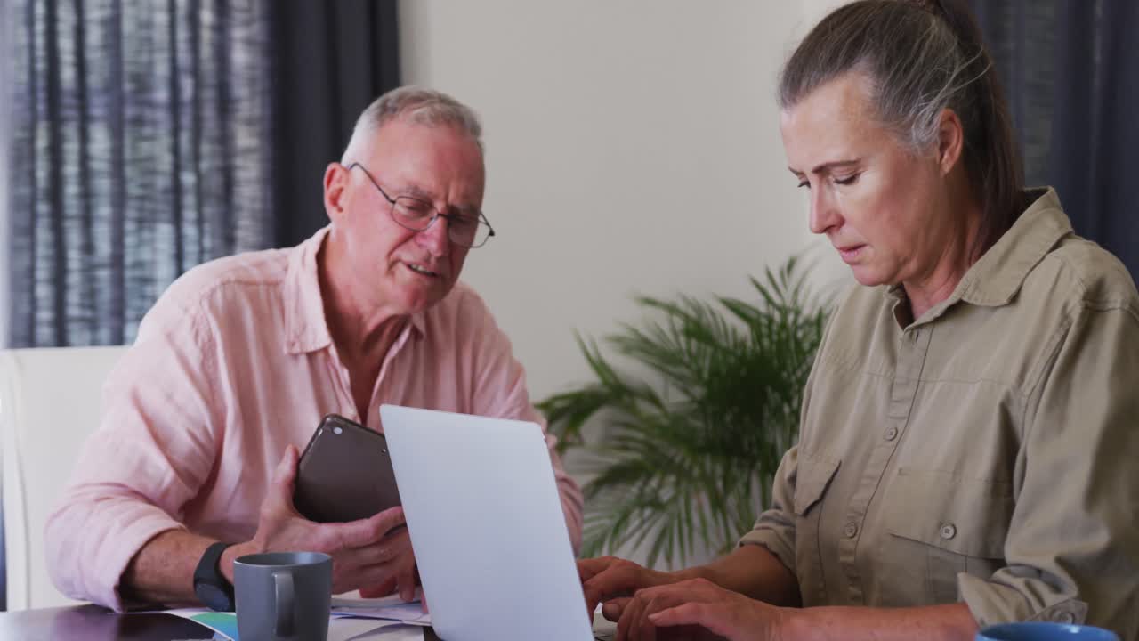 Caucasian senior couple using laptop and digital tablet at home
