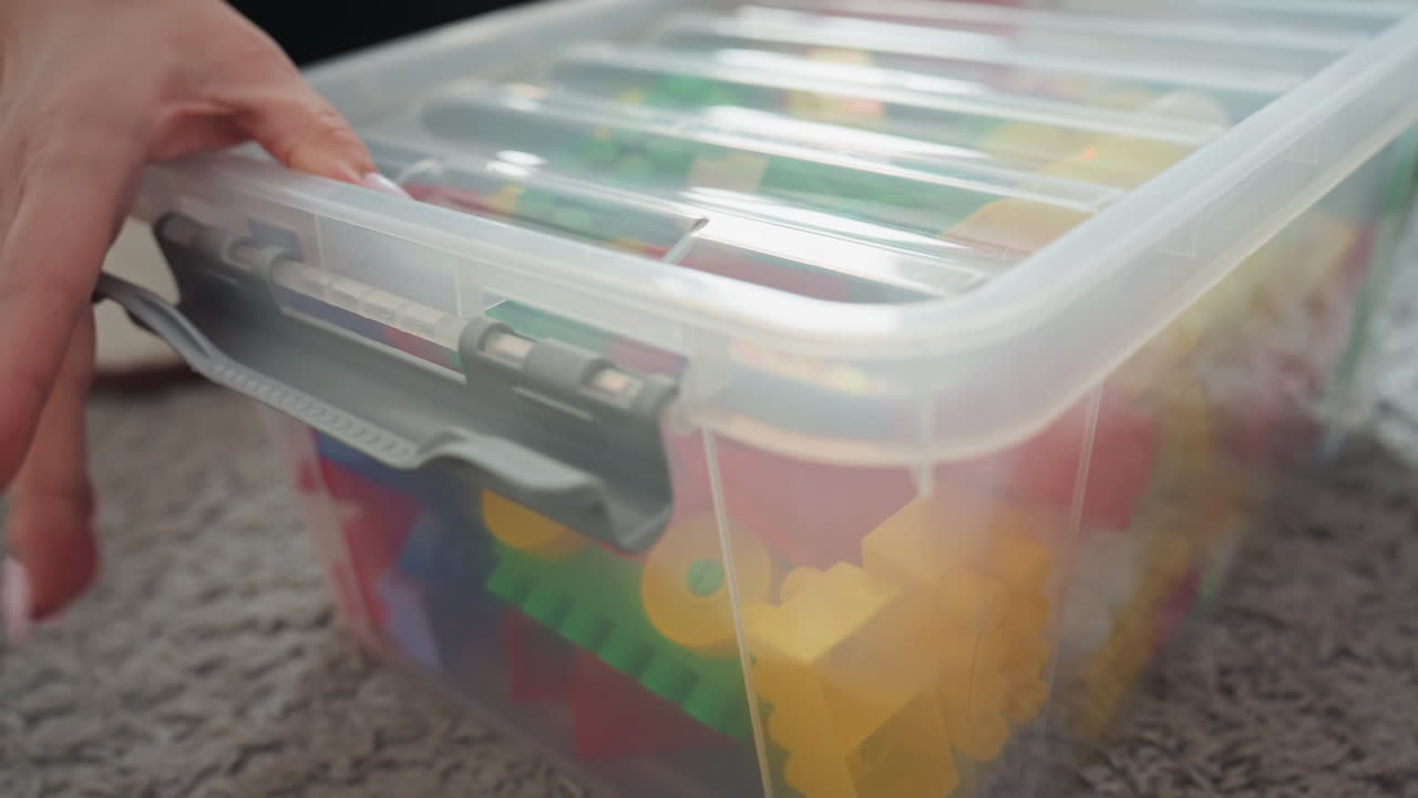 Kindersicherheitsverschluss fest eingerastet. Kindersicherung jetzt in Gebrauch. Sorgfältiges Verschließen des Spielzeugkistendeckels aus Gründen der Kindersicherheit. Hand verschließt den Spielzeugkistendeckel sicher, um Kinderzugang zu verhindern.