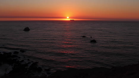 hermosa puesta de sol dorada a lo largo de la costa norte de california con un barco que cruza el sol y se encuentra con el horizonte en una tranquila noche de verano