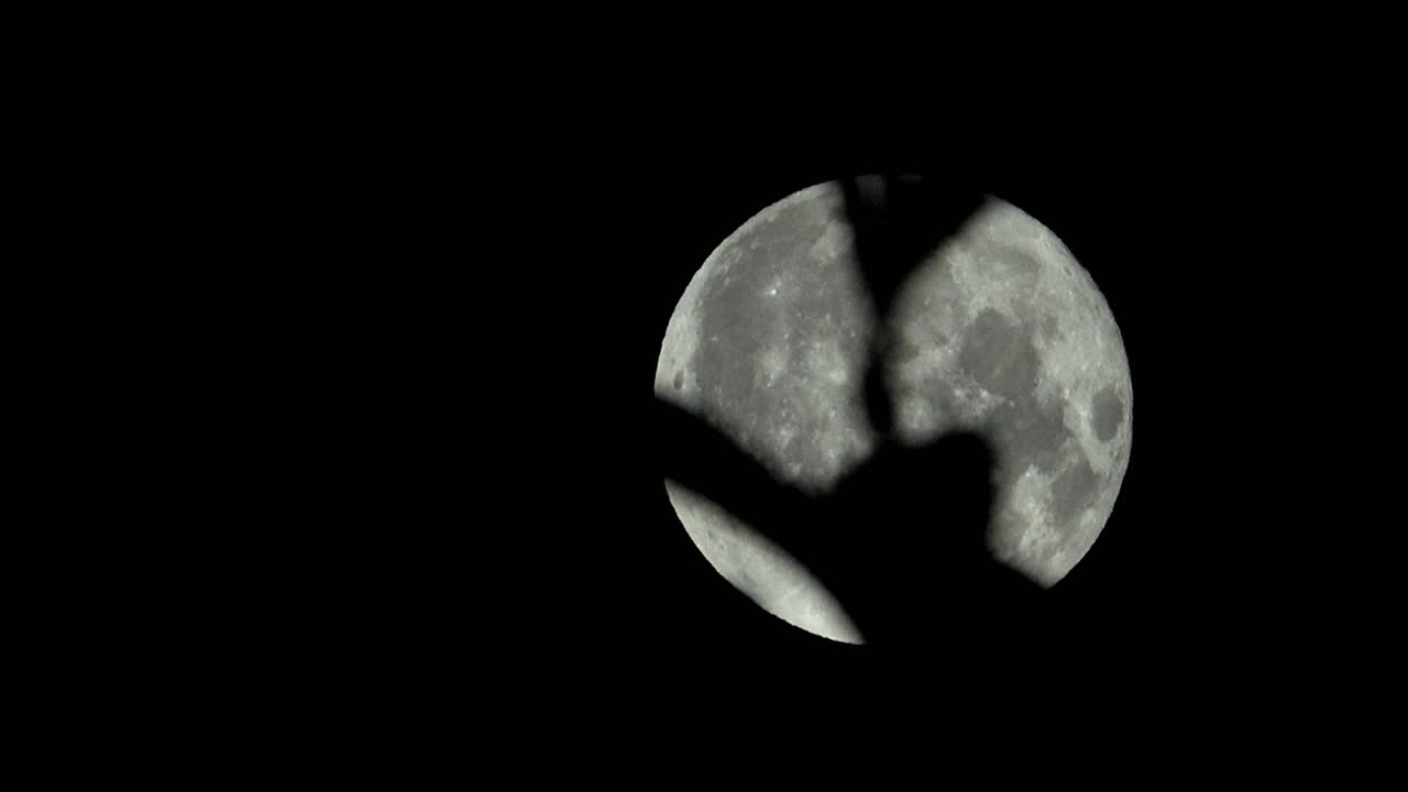 Full moon in July moving across the sky with leaves in foreground