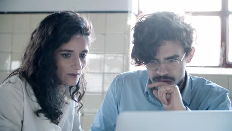 vista frontal de los jóvenes colegas sonrientes mirando la computadora portátil