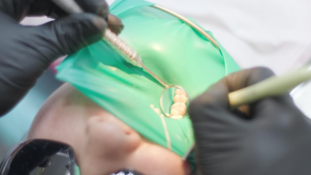 치과의사가 치과의사에서 환자의 치아를 검사합니다.