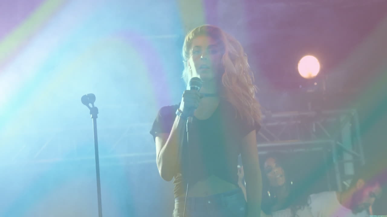 Kvinnelig sanger synger på en musikkbransjescene, med animerte lydbølge-ikoner over fagverk.