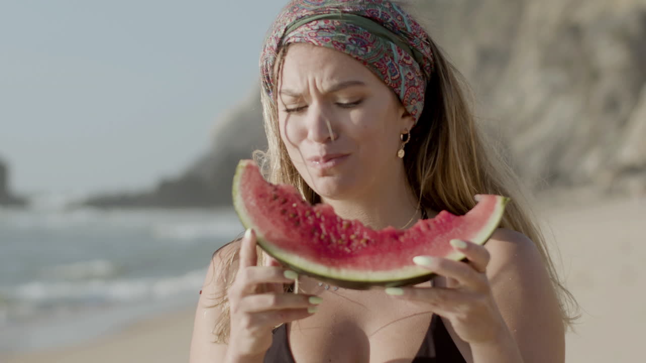 해안 에서 즐거움 으로 수박 을 먹고 있는 여자 의 앞면