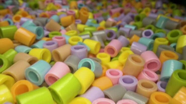 Dolly shot of short colorful plastic tube pieces stacked on top of each other. Plastic waste and recycling