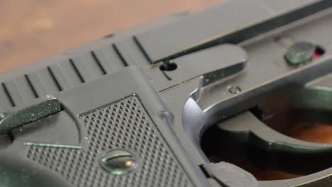 Closeup-dolly-across-handgun-weapon-to-trigger,-pistol-on-table-top