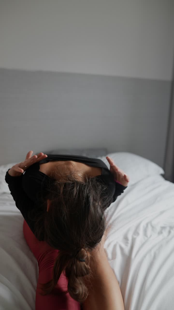 Woman practicing yoga on a bed