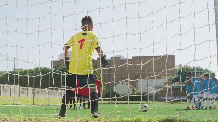 African American kid in blue scoring in a sunny day