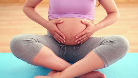 pregnant woman sitting on exercise mat