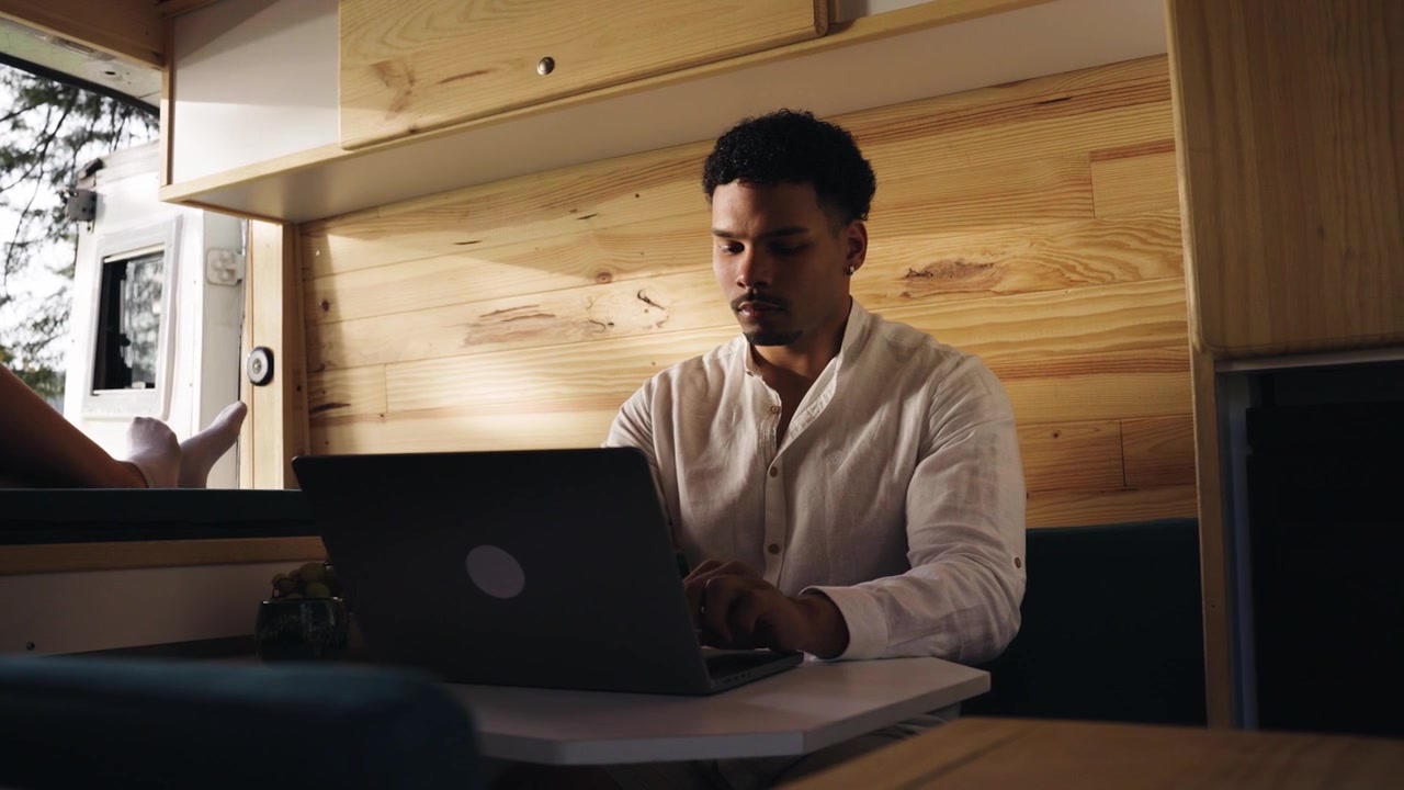 Young Man Working on Laptop Inside a Camper Van