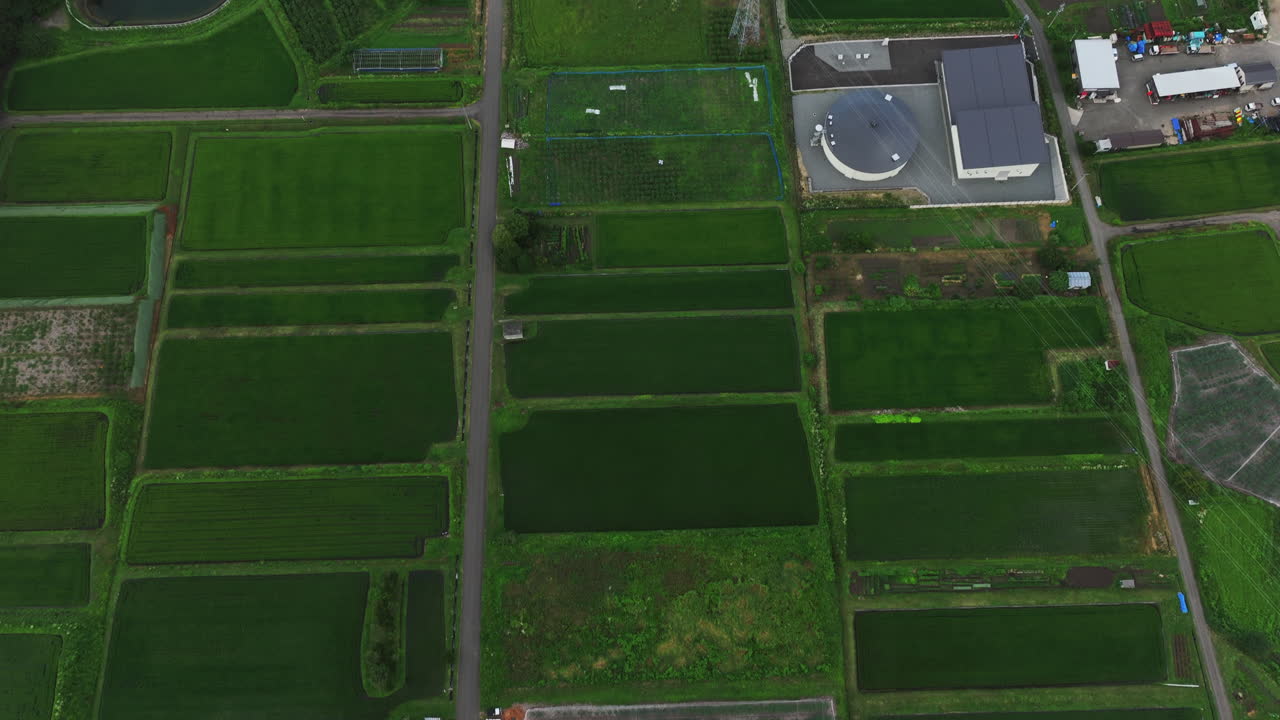 tilt aéreo disparado sobre campos de arroz, revelando una ciudad en el campo de nagano, japón