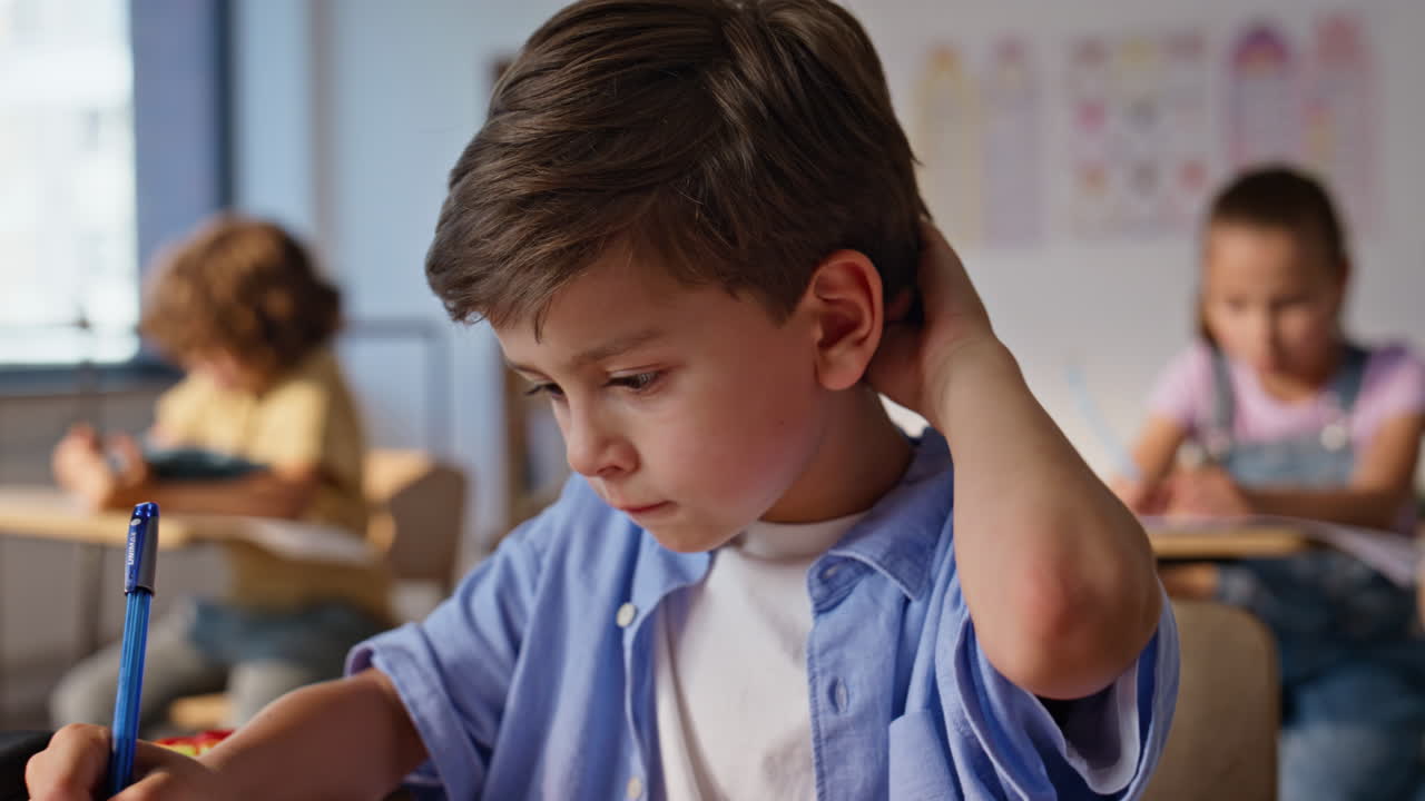Attentive boy studying lesson sitting classroom desk closeup. Schoolboy writing