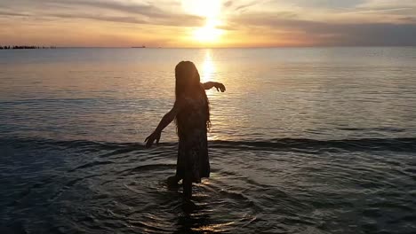 young lady dancing on the beach at sunset