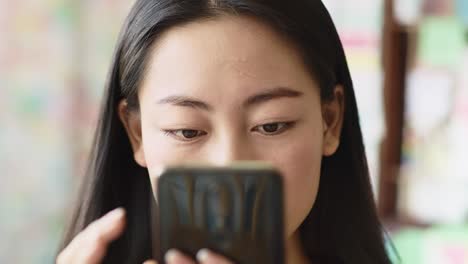 Handheld-view-of-Vietnamese-woman-looking-at-smart-phone