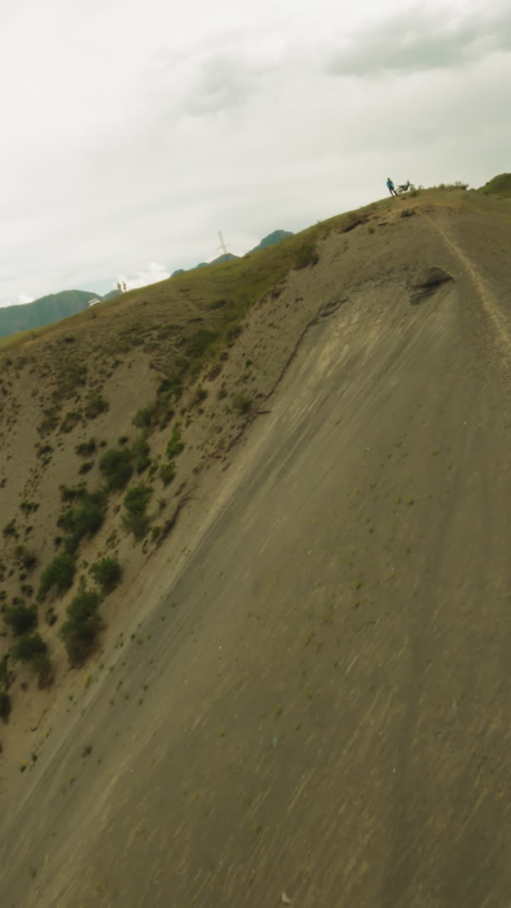 Dirt track and resting motorcyclist on hill ridge fpv. Sportsman with professional motorbike finishes route on mountain summit. Extreme sport hobby