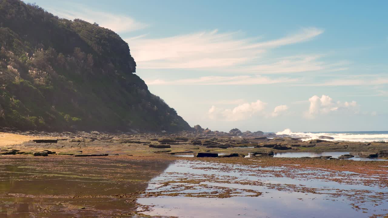 Slow motion landscape of trees bushland forest headland coastline with ocean beach bay and rocky reef sky horizon in Forresters Beach NSW Australia outdoors clouds travel tourism nature sea