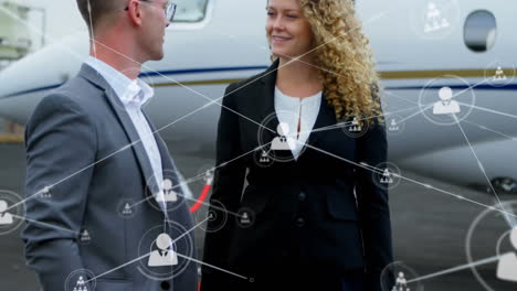 network of profile icons against caucasian businessman and businesswoman talking at airport runway