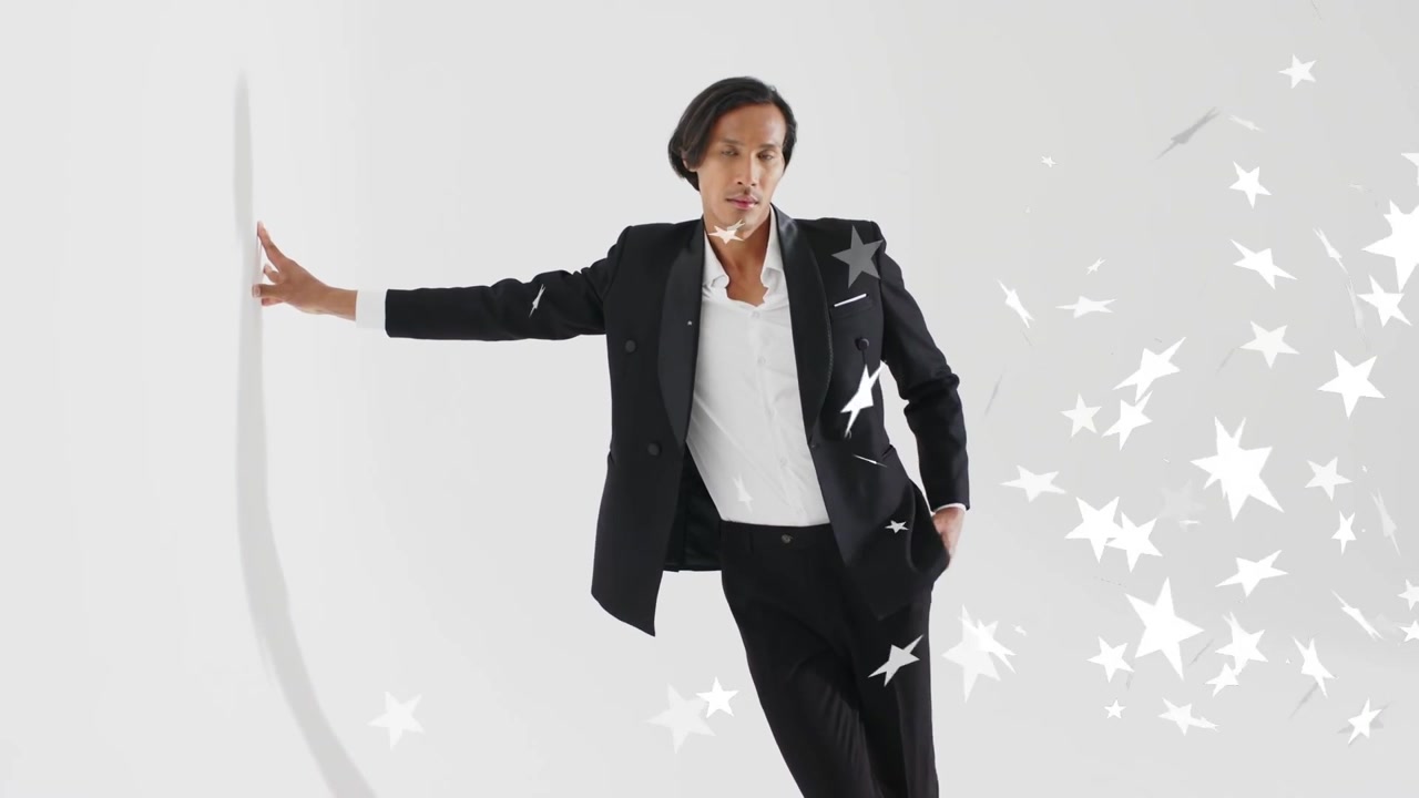 Uomo che tocca la cucitura, appoggiandosi, scivolando in tasca mentre le stelle si muovono, nascondendo l'abito, con la fotocamera che zooma sulla moda.