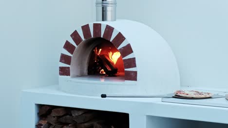 pizza oven with a fire burning inside and a pizza ready to bake