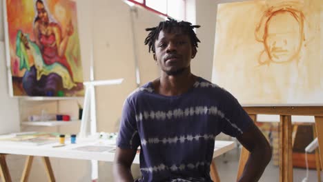 portrait of smiling african american male painter in artist studio