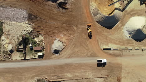 earth moving truck and earth moving tractor moving simultaneously through live quarry to complete their next task.