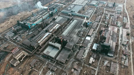 Aerial-View-Of-Industrial-Zone-With-Factories-Expelling-Smoke-Around-A-Green-Landscape-4