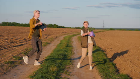 couple walking through countryside field with tablet and potted plant