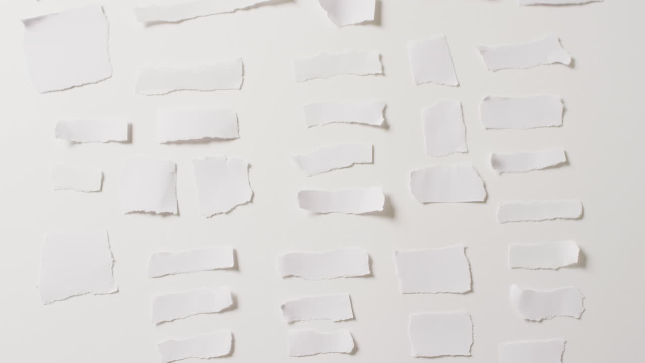video de un primer plano de varias piezas de papel rasgadas sobre un fondo blanco