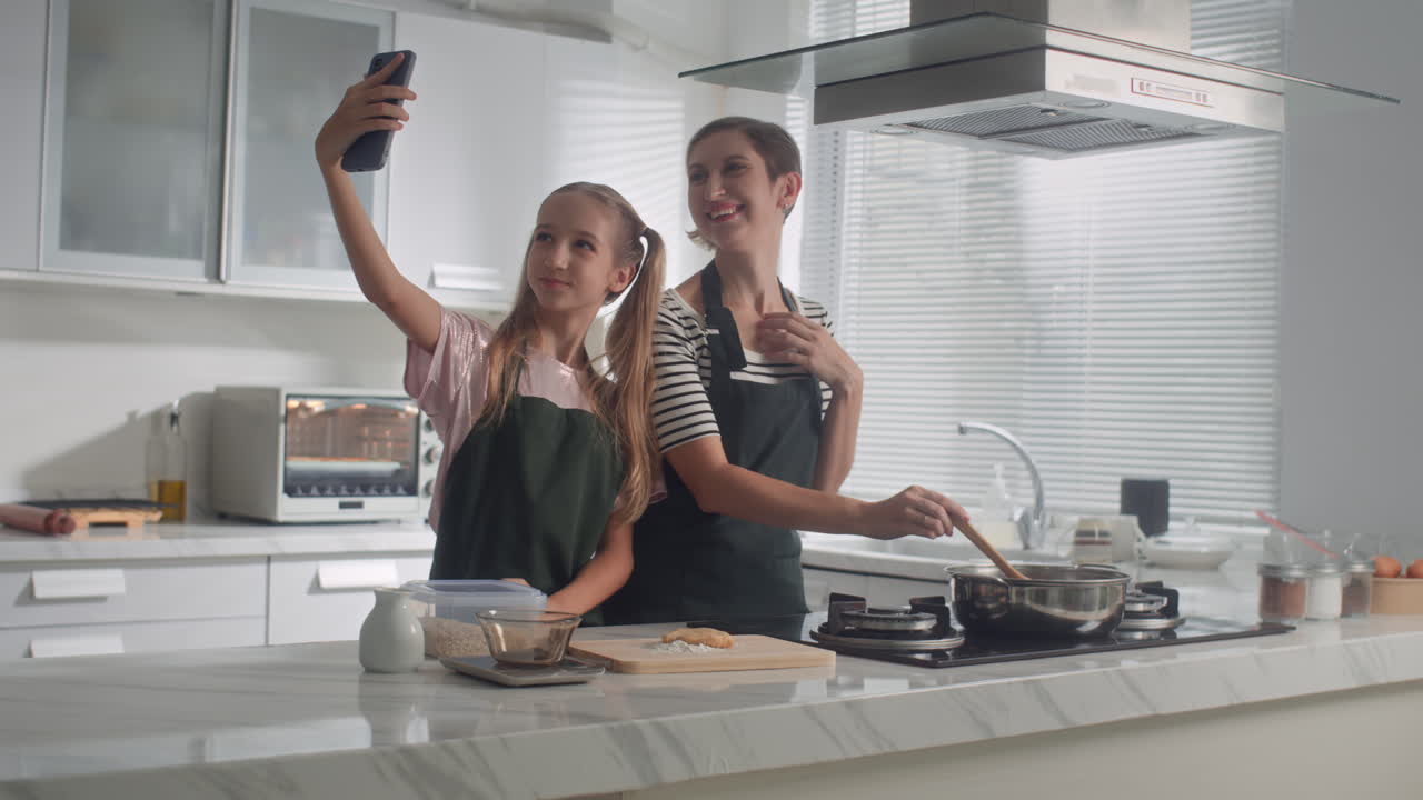 Ragazza che fa un selfie con la madre che cucina a cena in cucina