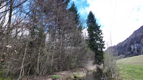 una vista panorámica revela un canal de agua que serpentea a través de las imponentes montañas suizas, encapsulando el concepto de serenidad y armonía con la naturaleza.