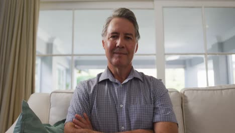 Smiling-senior-caucasian-man-sitting-in-living-room,-listening-during-a-video-call