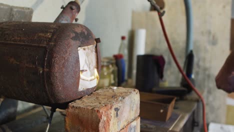 manos cercanas de un hombre caucásico fabricante de cuchillos en un taller usando un horno