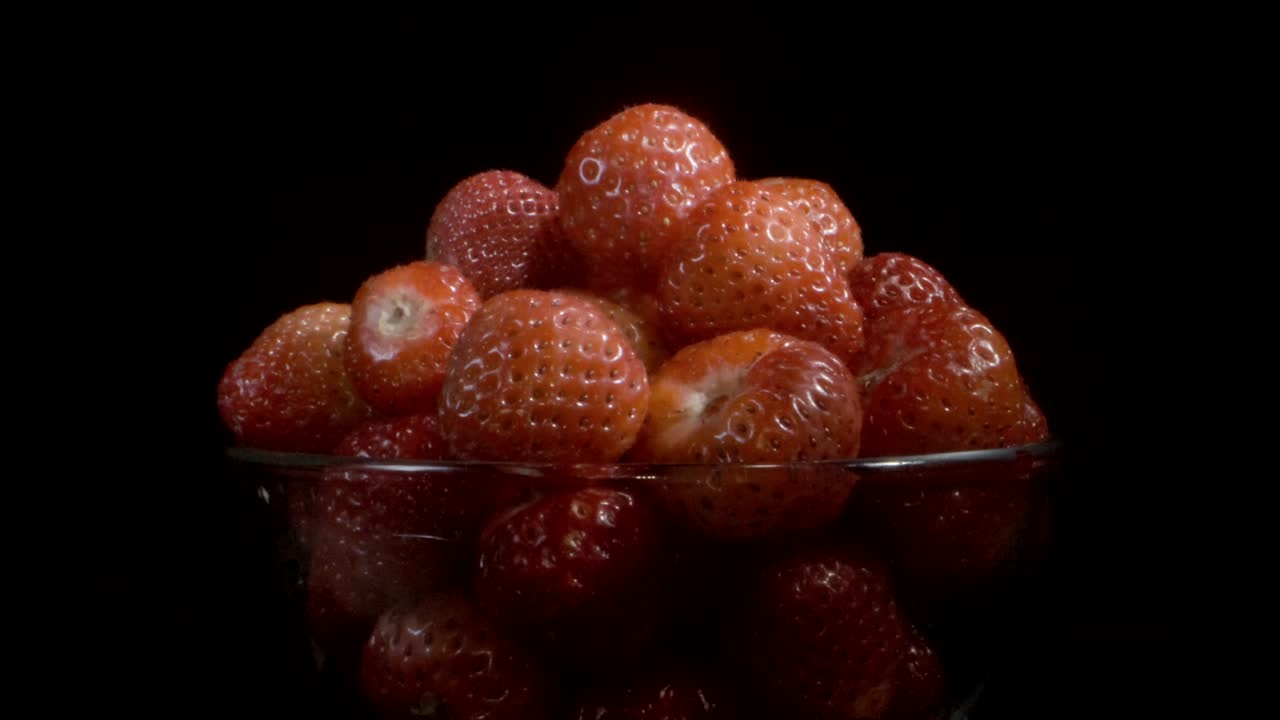 흑색 바탕에 은 스크린에서 빨간 딸기를 회전합니다. 카메라 회전 360도, 클로즈업.