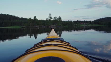 la proa de un kayak amarillo en un lago prístino durante la puesta de sol en noruega