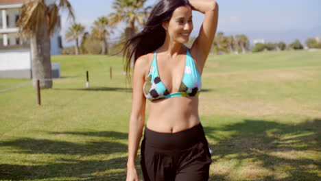 mujer en traje de playa posando en un terreno cubierto de hierba