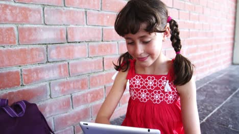 escolar que usa una tableta digital en el pasillo de la escuela