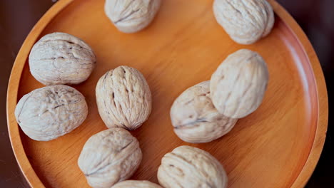 in a beautiful light, walnuts fall into the wooden plate in slow motion, top view and close up shot