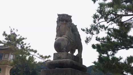 a pigeon flies off a komainu in miyajima, japan