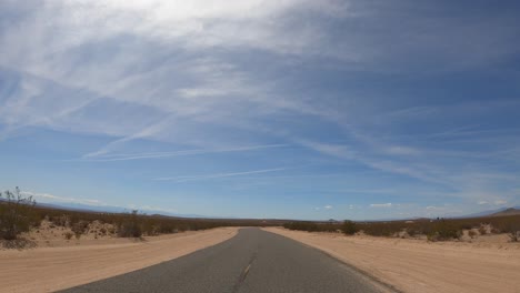 driving along a dusty and empty road in the middle of the desert- driver point of view