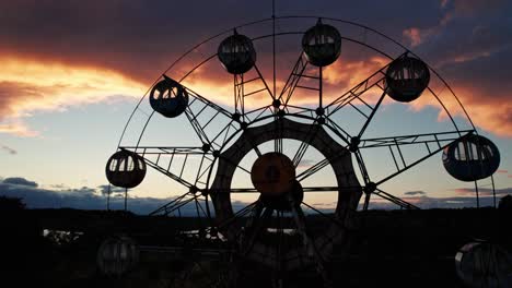 Primer-Plano-Drone-Mosca-Noria-Contrastada-Sobre-El-Horizonte-Del-Atardecer-En-Japón-Toma-Aérea-Del-Parque-De-Diversiones-Abandonado-Kejonuma