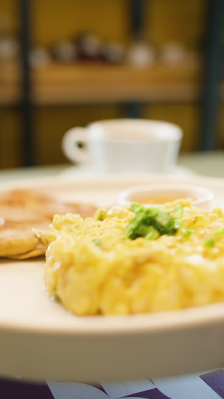 Breakfast plate with mote pillo, accompaniments and sauce in the foreground, with a cup of coffee and roast meat out of focus in the background