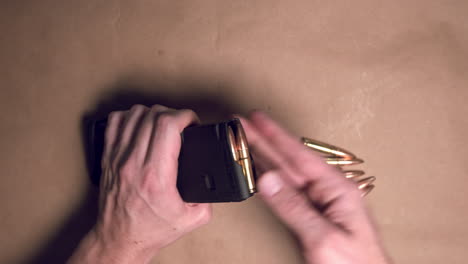 primer plano de manos cargando una revista de rifle con balas