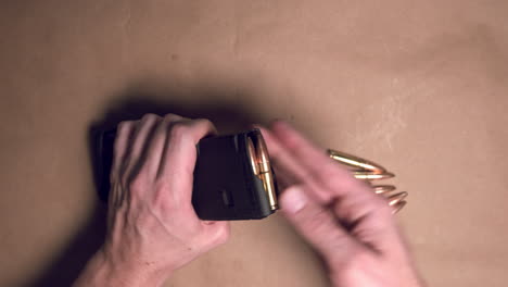 close up shot of hands loading a rifle magazine with bullets