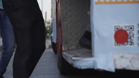 slow motion of people boarding city bus, closeup of legs, india
